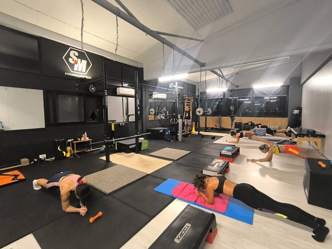 Lezione di gruppo di Strength and Movement in sala, con il rig S&M sullo sfondo
